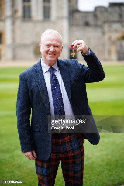 Alexander McLeish poses after being made an Officer of the Order of the British Empire during an investiture ceremony at Windsor Castle on April 9,...