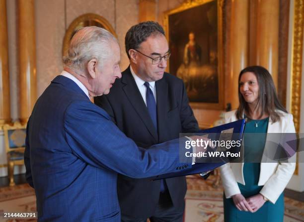 King Charles III is presented with the first bank notes featuring his portrait from the Bank of England Governor Andrew Bailey and Sarah John, the...