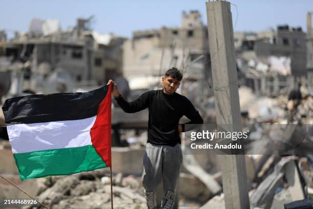 Palestinian child with Palestinian flag is seen amid destruction after Israeli forces' withdrawal from Khan Yunis, Gaza on April 09, 2024....