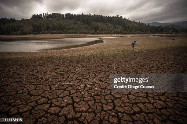 Man walks through a now dry section of the reservoir bed at Embalse La Regadera due to its historic low in the town of Usme on April 8, 2024 in...