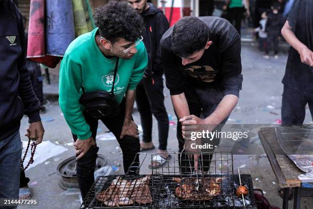 Youths grill meat to be sold as street food at a market in Deir el-Balah in the central Gaza Strip on the last day of the Muslim holy month of...