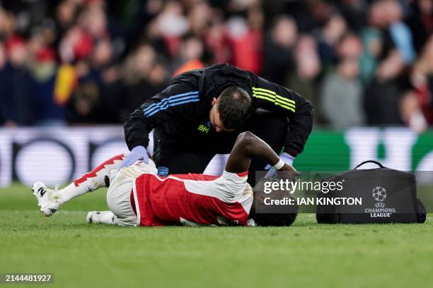 Arsenal's English midfielder Bukayo Saka receives medical treatment following a tackle by Bayern Munich's German goalkeeper Manuel Neuer during the...