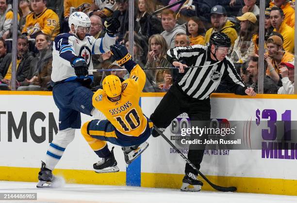 Adam Lowry of the Winnipeg Jets hits Colton Sissons of the Nashville Predators during an NHL game at Bridgestone Arena on April 9, 2024 in Nashville,...