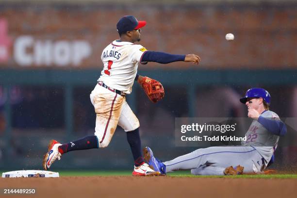 Ozzie Albies of the Atlanta Braves turns a double play as Brett Baty of the New York Mets slides into second during the seventh inning at Truist Park...
