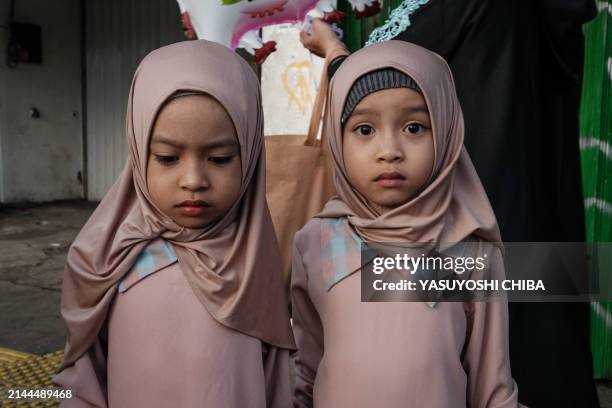 Muslim twin girls pose before Eid al-Fitr prayers, marking the end of the holy month of Ramadan, on a street in Jakarta on April 10, 2024.
