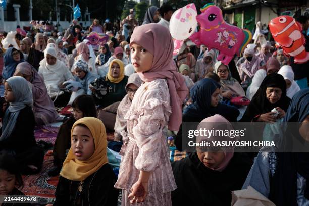 Muslim girl stands after Eid al-Fitr prayers, marking the end of the holy month of Ramadan, on a street in Jakarta on April 10, 2024.