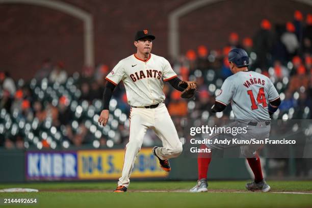 Wilmer Flores of the San Francisco Giants applies the tag on Ildemaro Vargas of the Washington Nationals in the top of the ninth inning at Oracle...