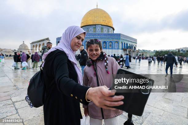 Muslim woman takes a selfie with a girl as they arrive to offer special morning prayers to start the Eid al-Fitr festival, which marks the end of the...