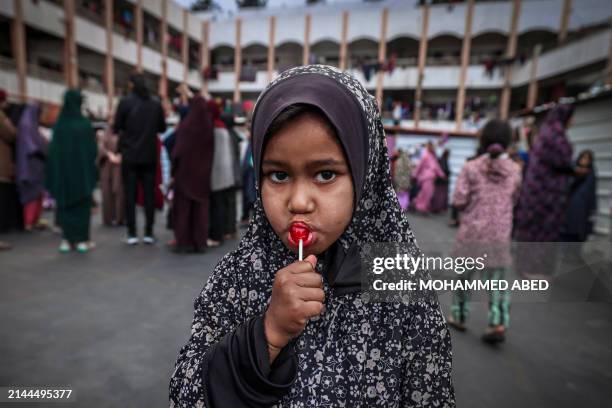 Displaced child licks a lollipop after a special morning prayer to start the Eid al-Fitr festival, marking the end of the holy month of Ramadan, at a...