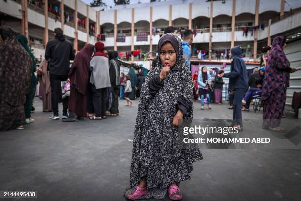 Displaced child licks a lollipop after a special morning prayer to start the Eid al-Fitr festival, marking the end of the holy month of Ramadan, at a...