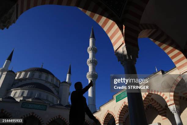Muslim man uses his smartphone walking on the grounds of the Cathedral Mosque during the Eid al-Fitr festival, which marks the end of the holy...