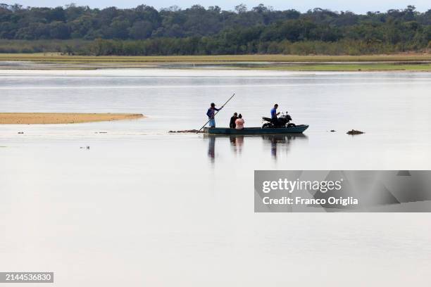 Fisherman ferries a motorcyclist on the Bita river on April 06, 2024 in Puerto Carreño, Colombia. Puerto Carreño is the departmental capital city,...