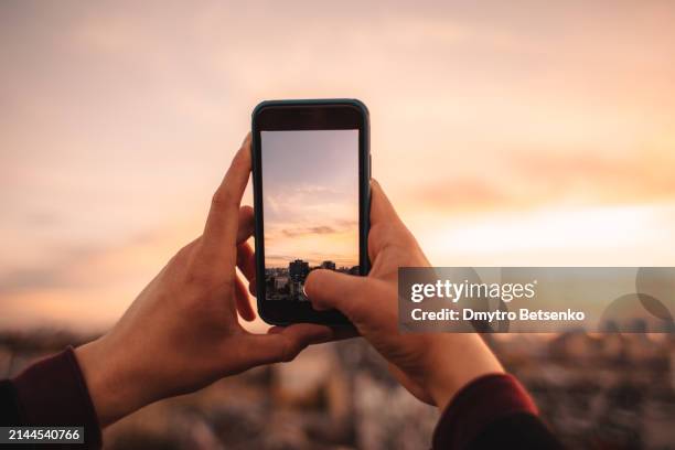 young man taking picture of city at sunset with smart phone - filming stock pictures, royalty-free photos & images