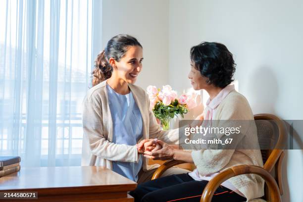 belle gardienne latine professionnelle parlant avec une patiente âgée asiatique dans une maison de retraite pour personnes âgées afin de se détendre et de se sentir consolante, ainsi que l’amitié pour des sentiments de détente et de bonheur. serv - soin du corps photos et images de collection