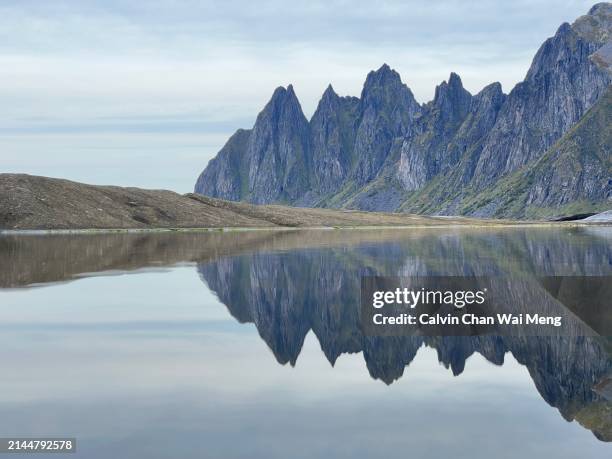 reflection view of the razor-sharp okshornan peaks also known as devil's teeth in tungeneset senja - northern norway - insel senja stock-fotos und bilder