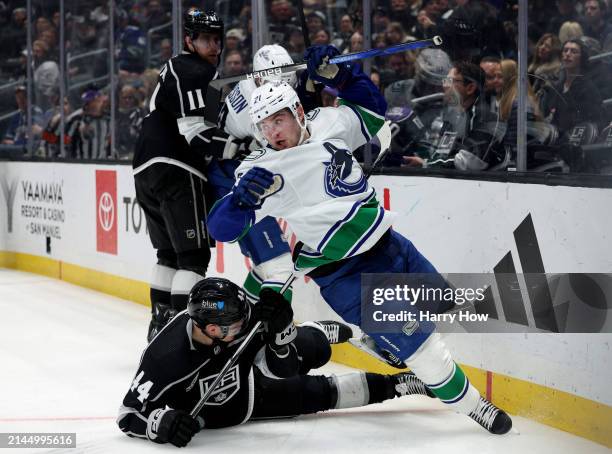 Nils Hoglander of the Vancouver Canucks loses his balance in front of Mikey Anderson and Anze Kopitar of the Los Angeles Kings during the third...