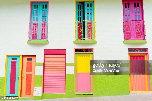 a colourful colonial house with pink wooden door and blue bay window in the old town of manizales, colombia - cultura sudamericana fotografías e imágenes de stock