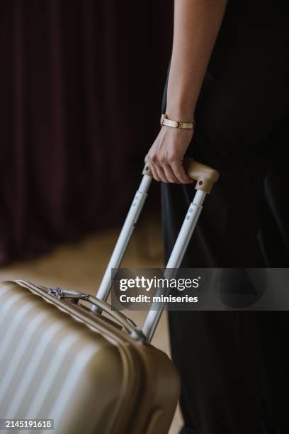 close up of an anonymous woman pulling a suitcase in a hotel room - koffer stockfoto's en -beelden