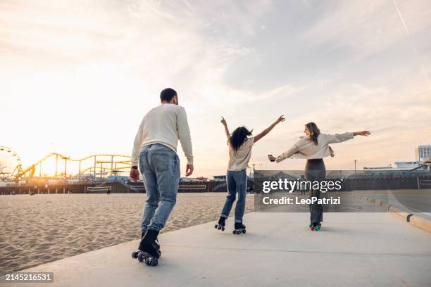 freunde rollschuhlaufen an der strandpromenade - santa monica pier stock-fotos und bilder