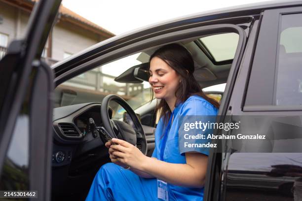 nurse using phone sitting on a car - flatten the curve imagens e fotografias de stock