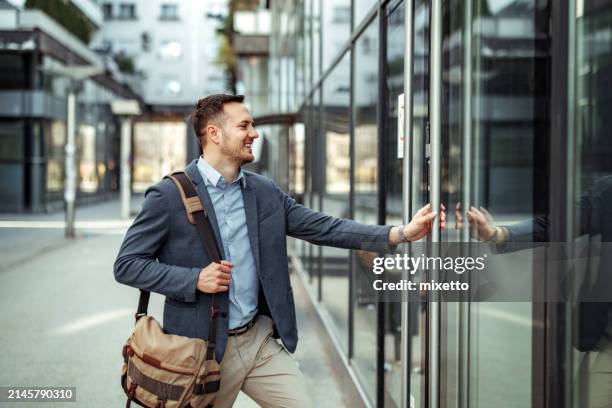 vista laterale di un bell'uomo d'affari ben vestito che apre la porta dell'azienda - entrare foto e immagini stock
