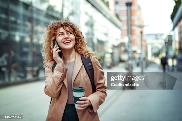 well dressed young businesswoman talking on a smart phone outdoors in a city - walkable city stock pictures, royalty-free photos & images
