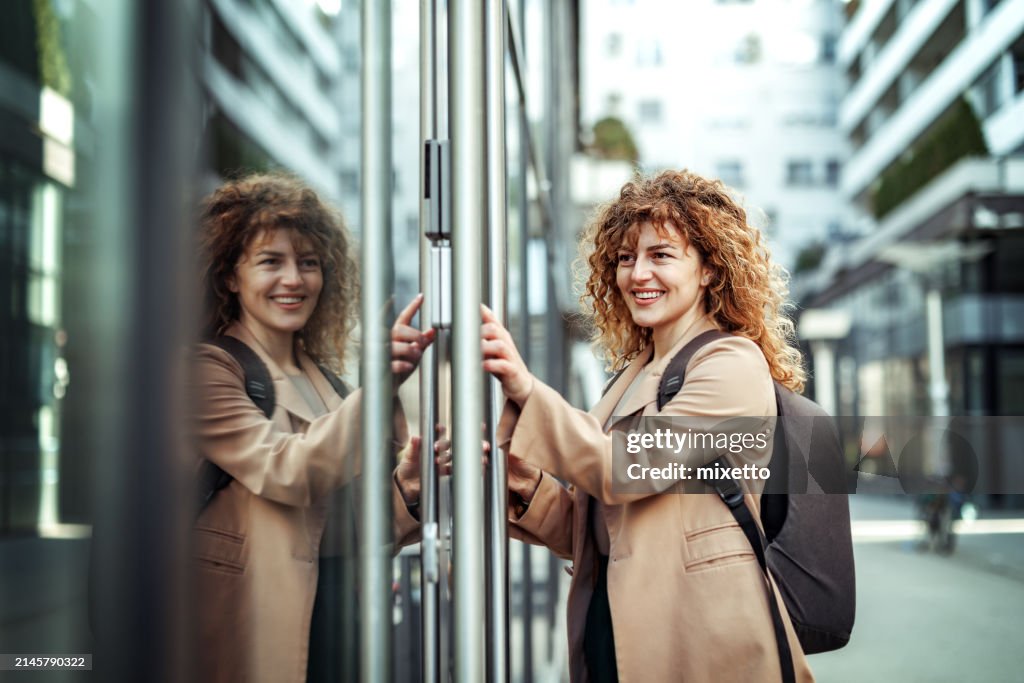 Vista lateral de la hermosa joven empresaria que ingresa el código PIN frente a las puertas de la empresa