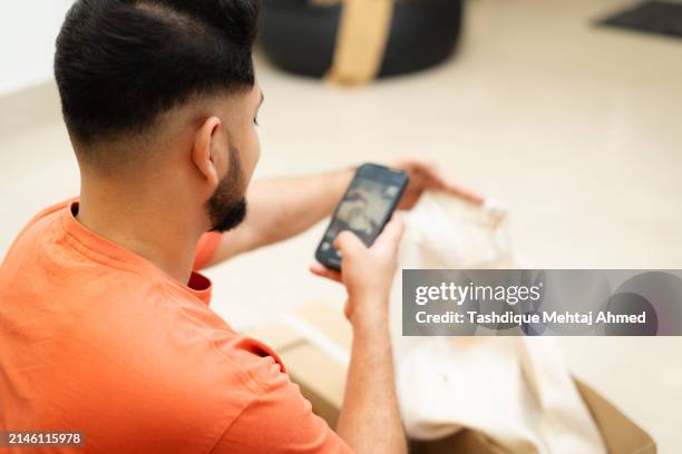 young indian man unboxing a parcel that he ordered online. - post office interior stock pictures, royalty-free photos & images