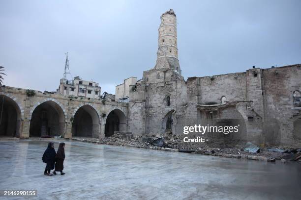 Two Palestinian girls walk on April 10, 2024 in prayer outfit in rainy weather through the courtyard of Gaza City's historic Omari Mosque, which has...