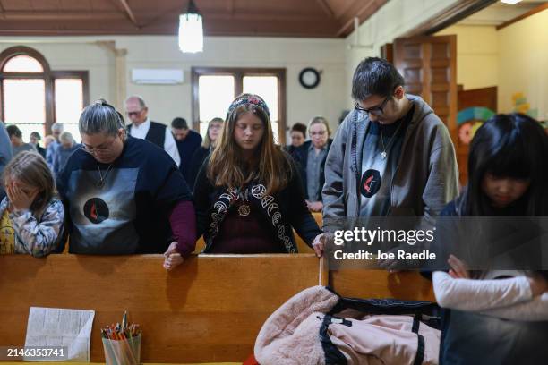 Isabella Alexander, Erica Alexander, Mallory Alexander, and Joey Alexander pray together during a mass held at the Houlton United Methodist Church on...
