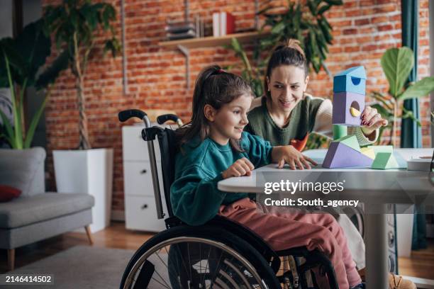 a joyful moment of learning and play, as a child in a wheelchair and mother engage with colorful geometric shapes on a table at home. - capacidades diferentes imagens e fotografias de stock