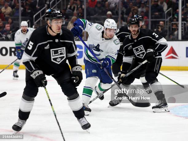 Nils Hoglander of the Vancouver Canucks looks for a pass between Matt Roy and Andreas Englund of the Los Angeles Kings during a 6-3 Kings win at...