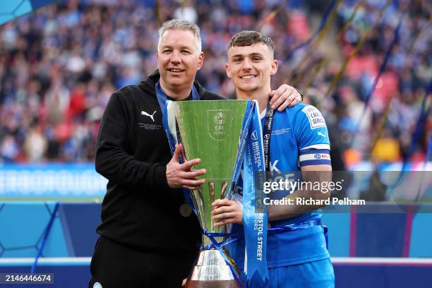 Darren Ferguson and Harrison Burrows of Peterborough United celebrate with the Bristol Street Motors Trophy after the team's victory during the...