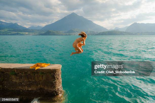 mujer saltando al lago en los alpes suizos - saltar actividad física fotografías e imágenes de stock