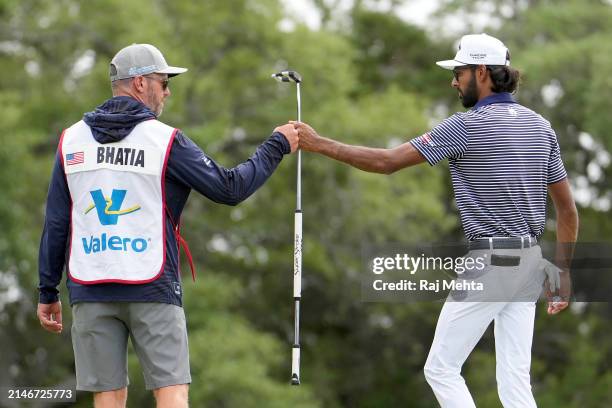 Akshay Bhatia of the United States fist bumps with his caddie after playing his putt shot on the 11th hole during the final round of the Valero Texas...