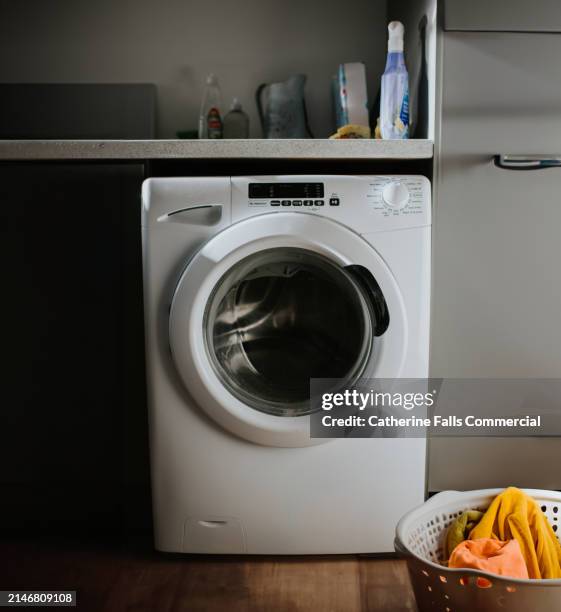 simple image of a modern washing machine and a washing basket filled with freshly laundered towels - tvättmaskin bildbanksfoton och bilder