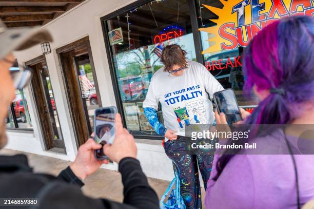 Travelers Brent and Toochis Rose take pictures of traveler Lynne Kueck's shirt ahead of the total solar eclipse on April 07, 2024 in Fredericksburg,...
