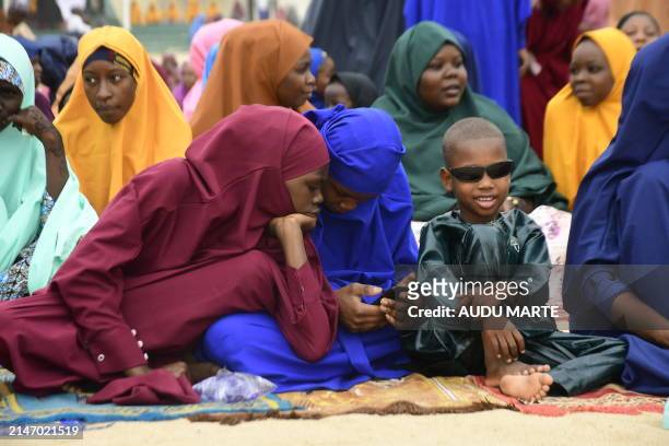 Young girls look at a phone while attending a special morning prayer to start the Eid al-Fitr festival, marking the end of the holy month of Ramadan...