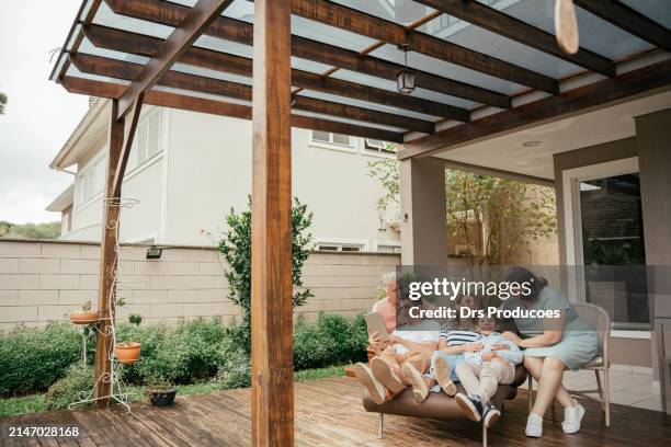 multigenerational family looking at tablet sitting on porch - porch stock pictures, royalty-free photos & images