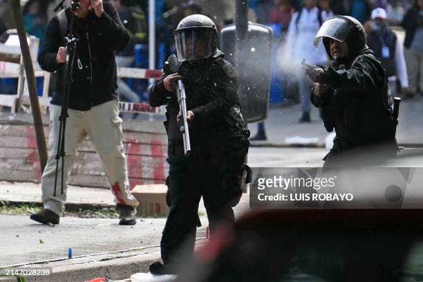 Policeman fires a rubber bullet against members of social organizations during a demonstration against the recent economic measures introduced by the...