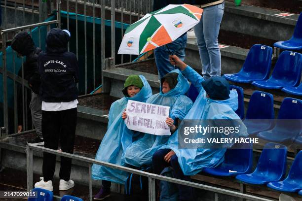Spectator holds a placard under an umbrella as matches are halted due to the rain during Denmark's Holger Rune and India's Sumit Nagal's Monte Carlo...