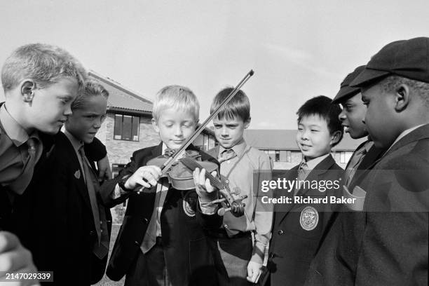 Boy shows his friends how he plays the violin in the playground of Bury Lawn School, on 21st September 1989, in Milton Keynes, England. Bury Lawn...