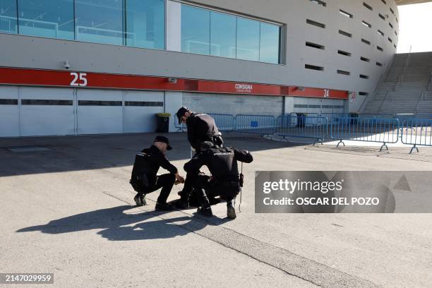 Spanish national police officers lift a manhole as they check the sewage system outside of the Metropolitano stadium prior to the UEFA Champions...