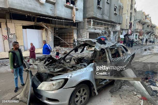 Onlookers check the car in which three sons of Hamas leader Ismail Haniyeh were reportedly killed in an Israeli air strike in al-Shati camp, west of...