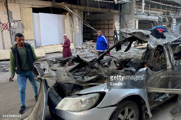 Onlookers check the car in which three sons of Hamas leader Ismail Haniyeh were reportedly killed in an Israeli air strike in al-Shati camp, west of...
