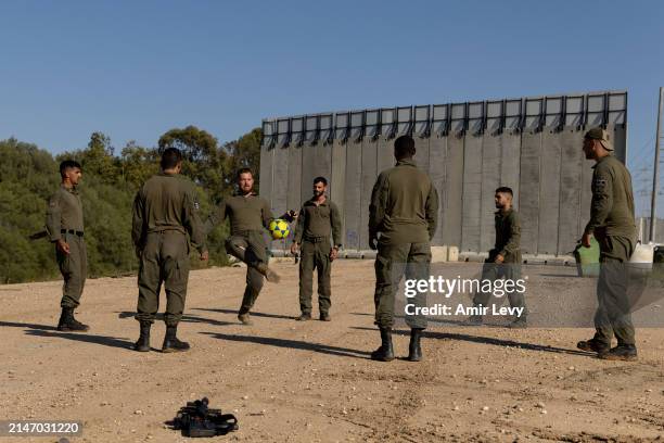 Israeli soldiers play with a ball near the border with the Gaza Strip on April 10, 2024 in Southern Israel. April 7th marks six months since Hamas...