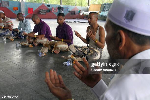 Rohingya ethnic refugees pray while eating together on the first day of the Eid al-Fitr at the Idi Sport Center temporary shelter in East Aceh,...