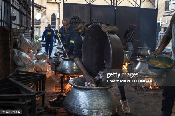 Muslim volunteer at the Saaberie Chishty Mosque pours meat in a large pot as he prepares meals to be distributed in a charity food distribution for...