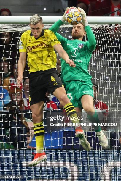 Atletico Madrid's Slovenian goalkeeper Jan Oblak jumps for the ball next to Dortmund's German defender Nico Schlotterbeck during the UEFA Champions...