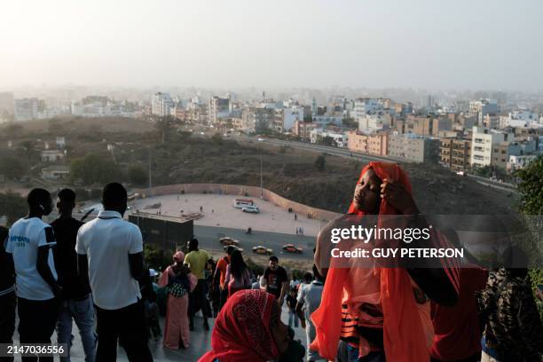 Woman adjusts her head scarf at the Monument de la Renaissance as Muslims celebrate Korite or Eid al-Fitr marking the end of the holy fasting month...